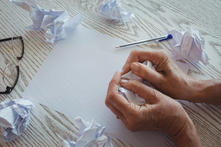 Close up of businesswoman crumpling papers on desk in officeの写真素材