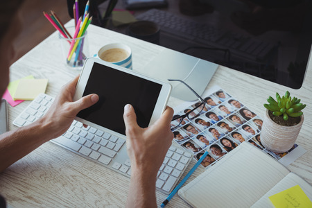 Cropped image of businessman using digital tablet at creative office deskの写真素材