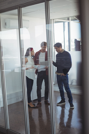 Full length of business colleagues seen through glass dicussing at officeの写真素材