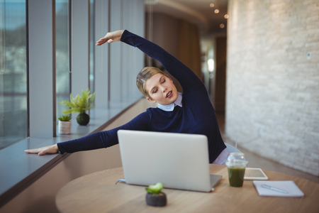 Executive stretching her hands while working in officeの写真素材
