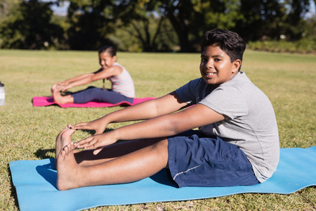 Portrait of boy touching toes during yoga glass on exercise mat at parkの写真素材