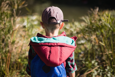 Rear view of boy wearing cap and hood standing in forestの写真素材