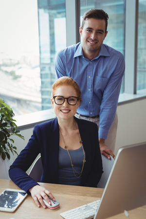 Portrait of smiling executives working at desk in officeの写真素材