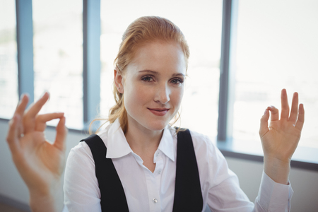 Portrait of smiling executive performing yoga in officeの写真素材