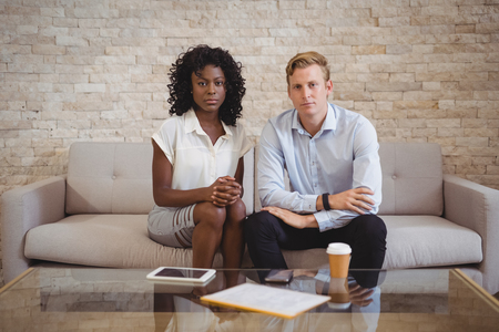 Portrait of confident executives sitting on sofa in officeの写真素材