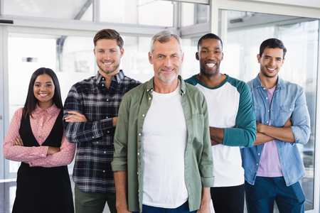 Portrait of smiling business people with arms crossed standing in officeの写真素材