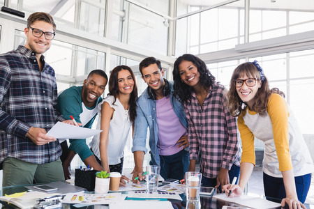 Portrait of young business team discussing at table in creative office