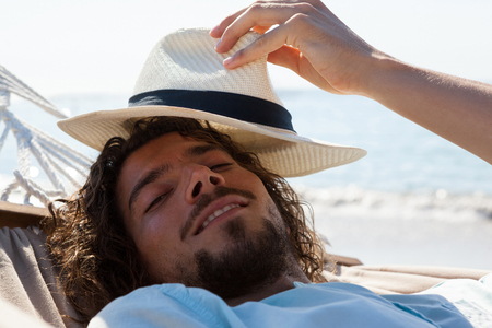 Portrait of smiling man relaxing in hammock on beachの写真素材