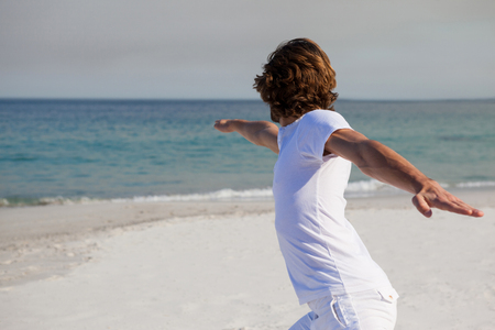 Man performing yoga at beach on a sunny dayの写真素材