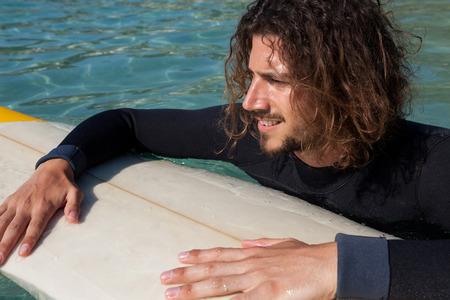Smiling surfer leaning on surfboard in seaの写真素材