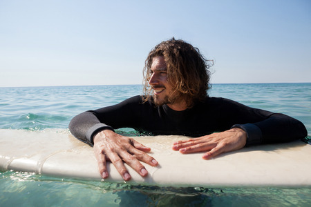 Smiling surfer leaning on surfboard in sea