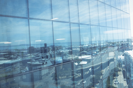Full frame shot of office building exterior with reflection of city against sky