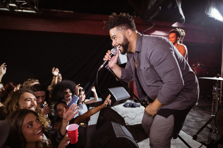 Young singer performing for fans at nightclub during music festivalの写真素材
