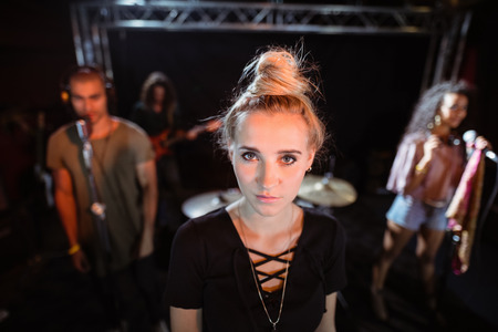 Young woman standing with musicians in background at nightclubの写真素材