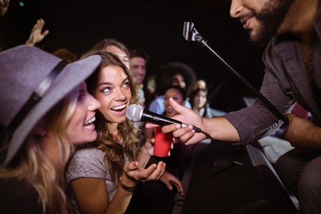 Female friends singing with male singer at nightclub during music festivalの写真素材