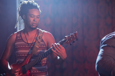 Male guitarist playing guitar at nightclub during music concertの写真素材