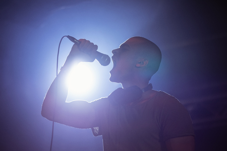Cheerful male singer performing at nightclub during music festivalの写真素材