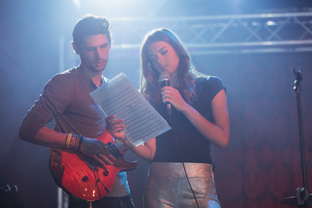 Female singer with male guitarist practicing at nightblubの写真素材