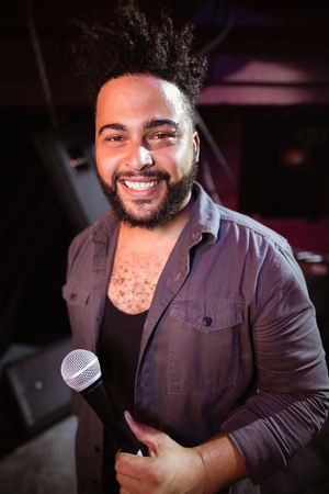 Portrait of singer holding mic at nightclub during music festivalの写真素材