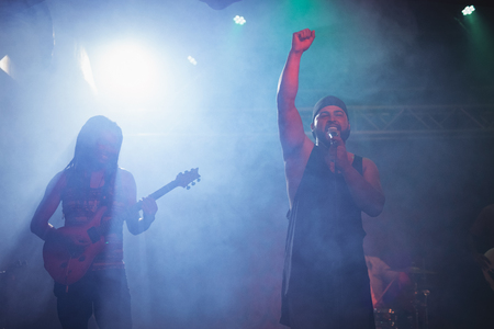 Cheerful musicians performing while standing at nightclubの写真素材