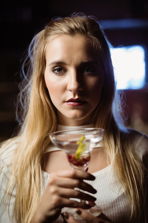 Close up portrait of woman with martini glass standing in clubの写真素材