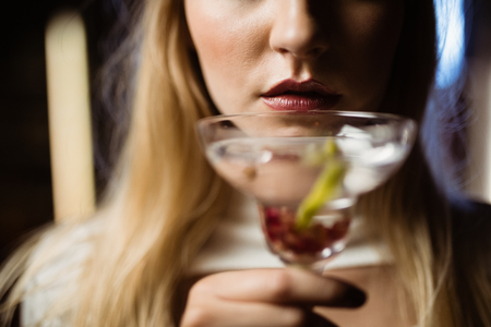 Midsection of woman holding martini glass in nightclubの写真素材
