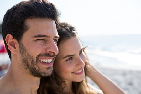 Thoughtful young couple looking away at beachの写真素材
