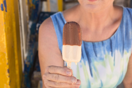Midsection of woman holding ice cream while sitting at beach hutの写真素材
