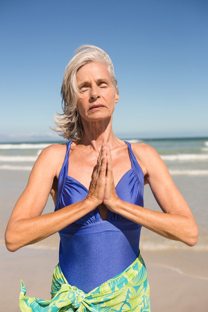 Close up of woman with hands clasped standing against clear sky at beachの写真素材