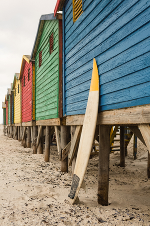 Surfboard by blue wooden hut on sand at beachの写真素材