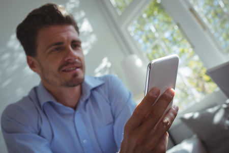 Handsome man using mobile phone in restaurantの写真素材