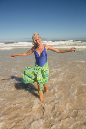Portrait of smiling woman walking on shore against clear sky at beachの写真素材