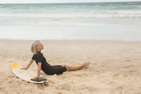 Side view of woman leaning on surfboard at beachの写真素材