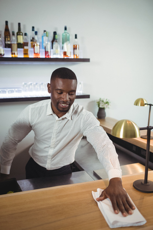 Bar tender cleaning bar counter in restaurantの写真素材