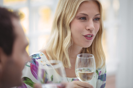 Woman interacting while having wine during lunch at restaurantの写真素材