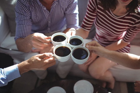 Friend toasting coffee cups together at restaurantの写真素材