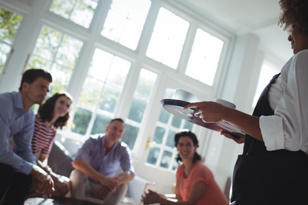 Waitress serving coffee to customers in restaurantの写真素材