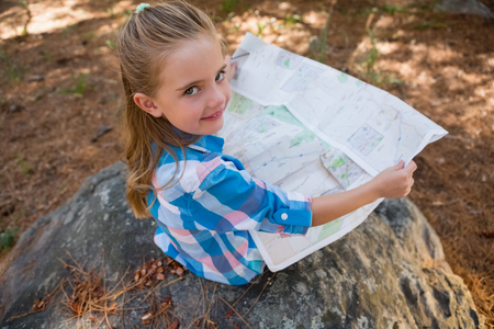 Portrait of smiling girl reading the map in the forest