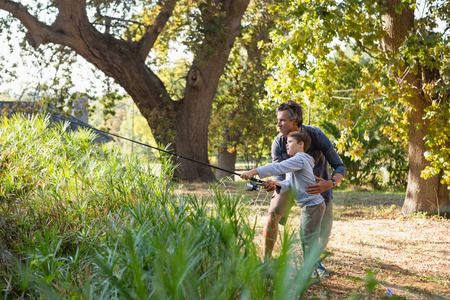 Father and son fishing in the river in forestの写真素材