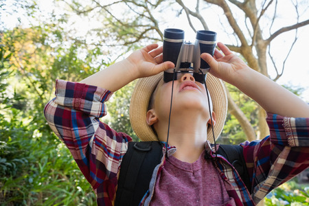 Close-up of boy looking through binoculars in the forest