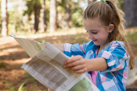 Smiling girl reading the map in the forestの写真素材