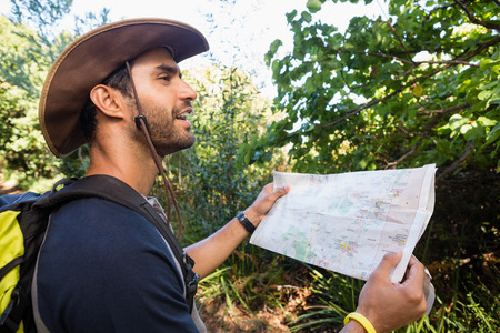 Man holding the map and looking at the distance in the forestの写真素材