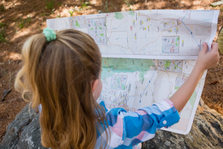 Rear view of girl reading the map in the forestの写真素材