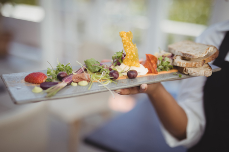 Mid section of waitress holding food tray in restaurantの写真素材