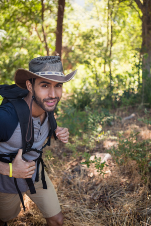 Portrait of smiling man with backpack walking in the forest on a sunny dayの写真素材