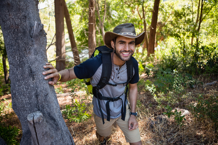 Portrait of smiling man with backpack walking in the forest on a sunny dayの写真素材