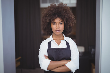 Portrait of confident waitress standing with arms crossed in restaurantの写真素材