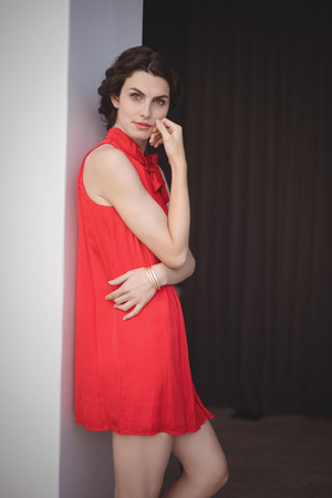 Portrait of beautiful woman in red dress standing in restaurantの写真素材