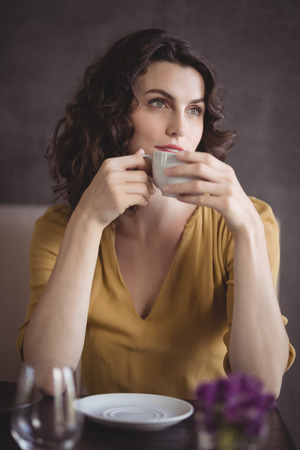 Thoughtful woman having coffee in restaurantの写真素材