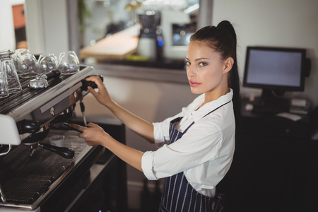 Portrait of smiling waitress preparing espresso at restaurantの写真素材